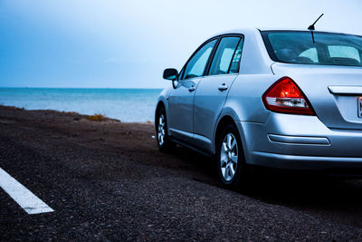 Car on road by sea against sky