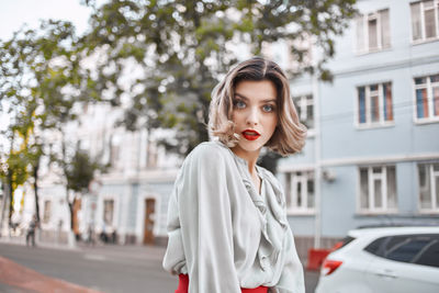 Portrait of beautiful woman standing against building