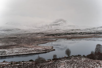 Scenic view of lake by snowcapped mountain against sky