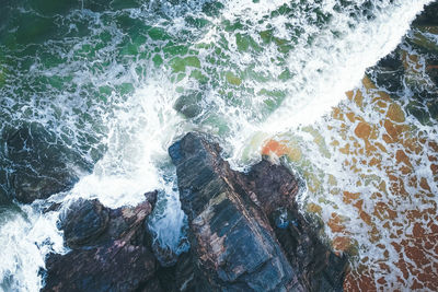 High angle view of waves splashing on rocks