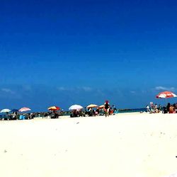 View of people at beach against blue sky