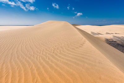 Scenic view of sand dunes against sky