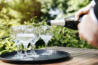 Cropped image of person pouring champagne in glass at table