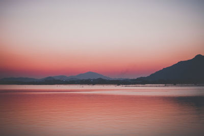 Scenic view of lake against romantic sky at sunset