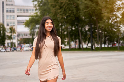 Portrait of smiling young woman standing in city