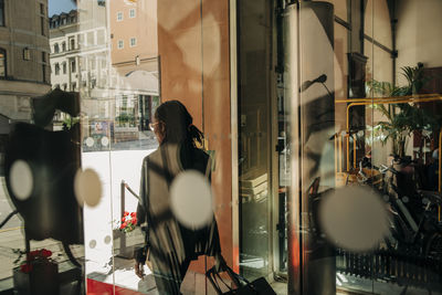 Rear view of young businesswoman with suitcase leaving hotel