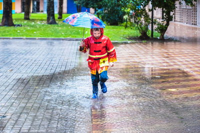 Full length of boy with umbrella during monsoon