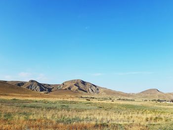 Scenic view of arid landscape against clear blue sky