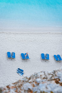 Hooded chairs on beach against blue sky