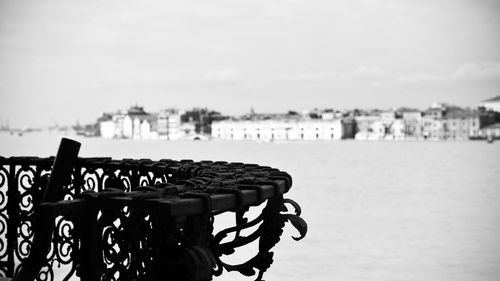 Close-up of railing by sea against sky in city