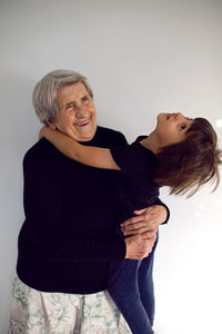 Funny grandson in a black t-shirt stands next to an old grandmother