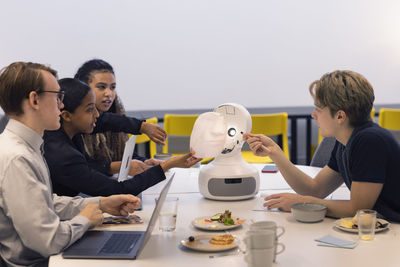 Business people discussing robot voice assistant during meeting