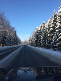 Road amidst snow covered trees against sky