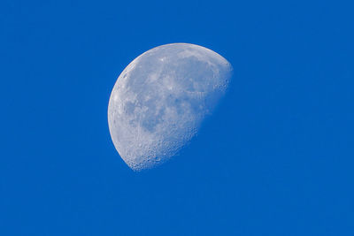 Low angle view of moon against clear blue sky