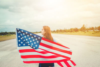 Young woman holding american flag on road