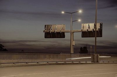 Illuminated street lights against sky at dusk