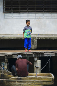 View of boy standing on pier in harbor