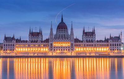 Hungarian parliament building by river in city at dusk