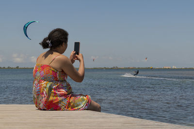 Rear view of woman standing at beach against clear sky