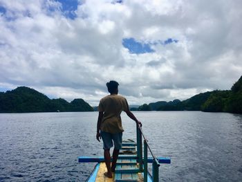 Rear view of man standing against sky in a boat