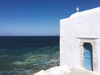 Building by sea against clear blue sky