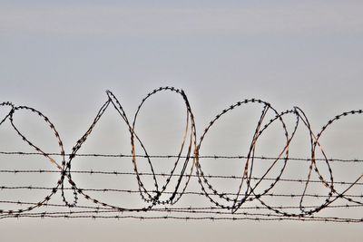 Low angle view of razor fence on barbed wire against clear sky