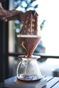 Close-up of hand pouring coffee cup on table