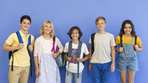 Portrait of happy friends standing against blue sky