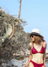 Woman standing by tree against clear sky