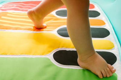 Low section of baby boy walking on piano designed mat