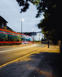 Illuminated road by building against sky at night