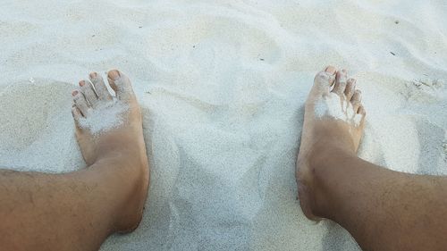 Low section of people relaxing on sand at beach