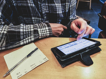 Midsection of man using mobile phone on table