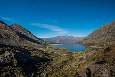 Scenic view of lake and mountains against blue sky