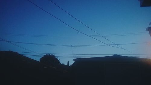 Low angle view of silhouette cables against clear sky