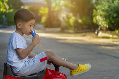 Boy eating while sitting on toy car