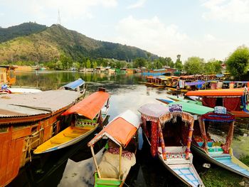 Boats moored in sea in front of mountains against sky