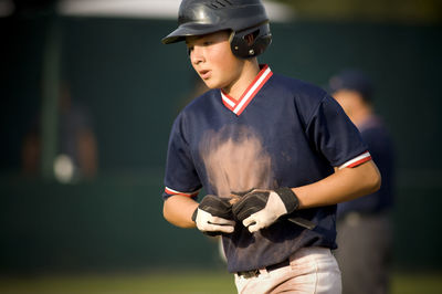 Close-up of young baseball player with dirty jersey jogging off the field