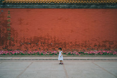 Rear view of woman standing against wall