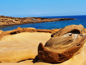 Rocks on beach against clear sky