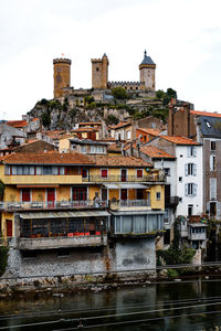Buildings by river in town against sky