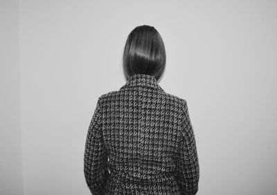 Rear view of woman wearing jacket while standing by wall