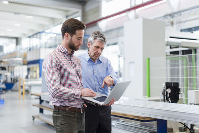 Businessmen using laptop in production hall