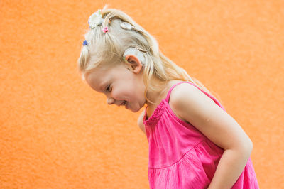 Young woman standing against yellow wall