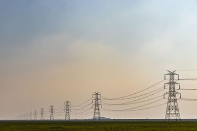 Low angle view of electricity pylon on field against sky