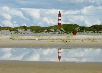 Lighthouse by puddle against sky