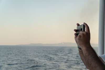 Cropped hand of person photographing while standing in boat