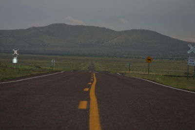 Empty road by mountains against sky