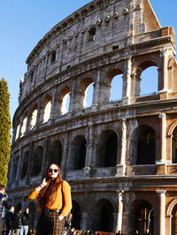 Low angle view of woman standing against coliseum