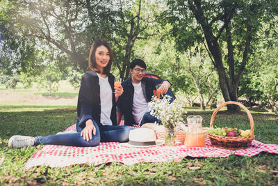 Portrait of smiling couple with objects resting on field